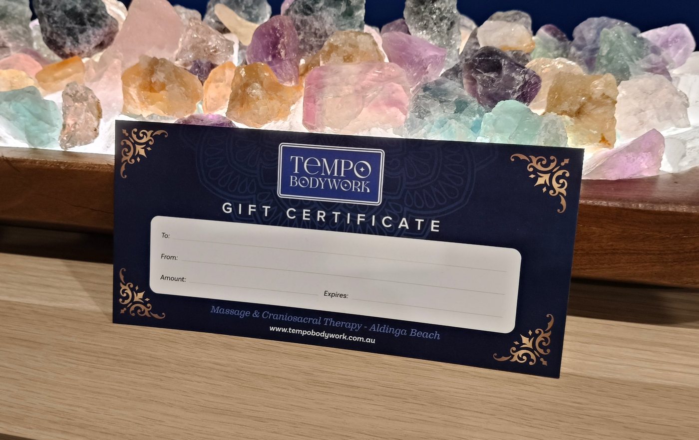 A Tempo Bodywork gift certificate in front of the studio's glowing crystal lamp